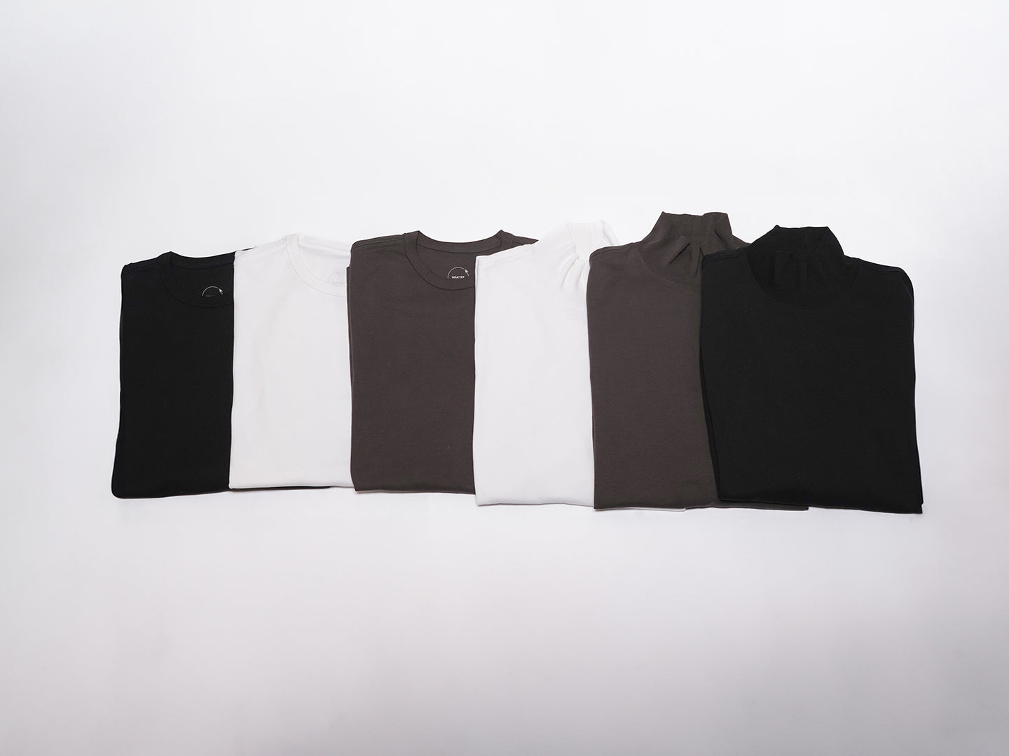 folded MakTee shirts in assorted colors laid out horizontally over each other